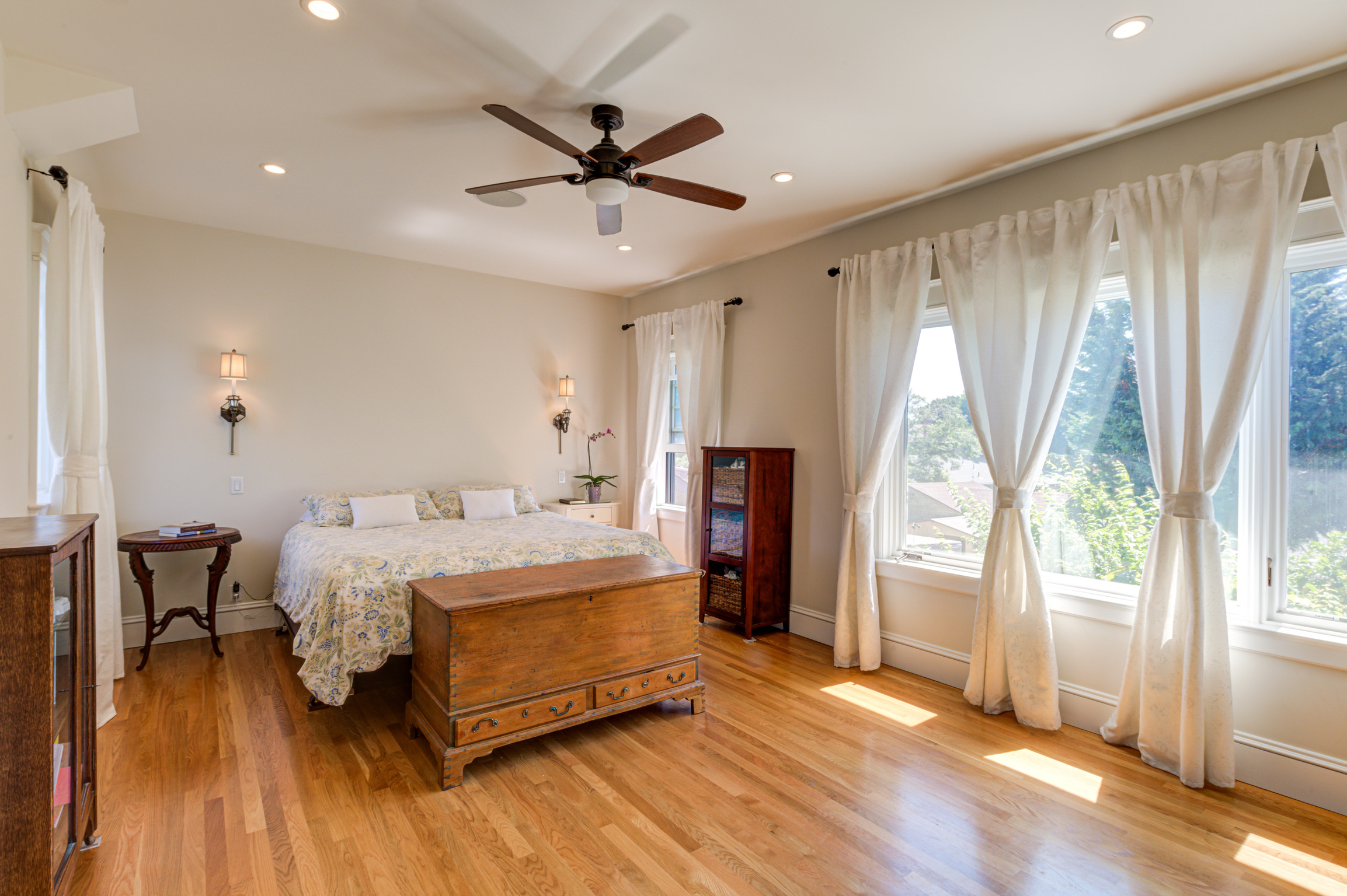 Alameda Addition bedroom with hardwood floors, ceiling fan, two windows for natural light, and sconce-ready wiring.