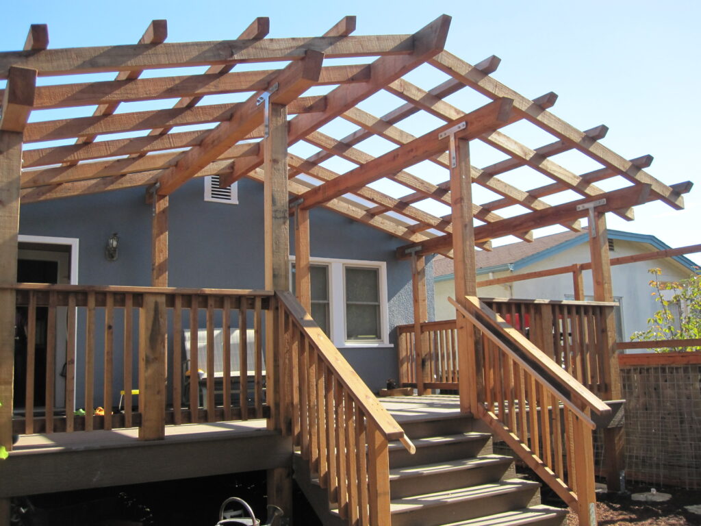 Pergola framework adds covered outdoor space; connected to porch with railings and stairs providing direct yard access and flow.