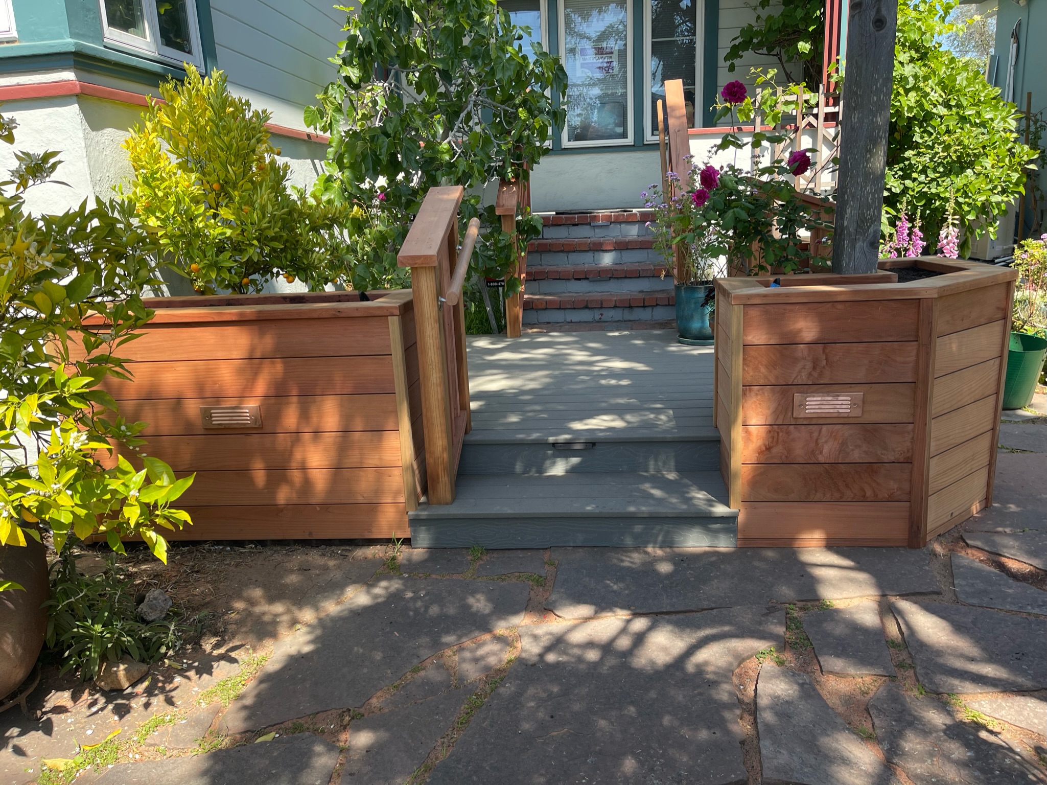 Ramp with planter boxes provides accessible entry to front deck and stairs; landscaping offers privacy for the Berkeley property.