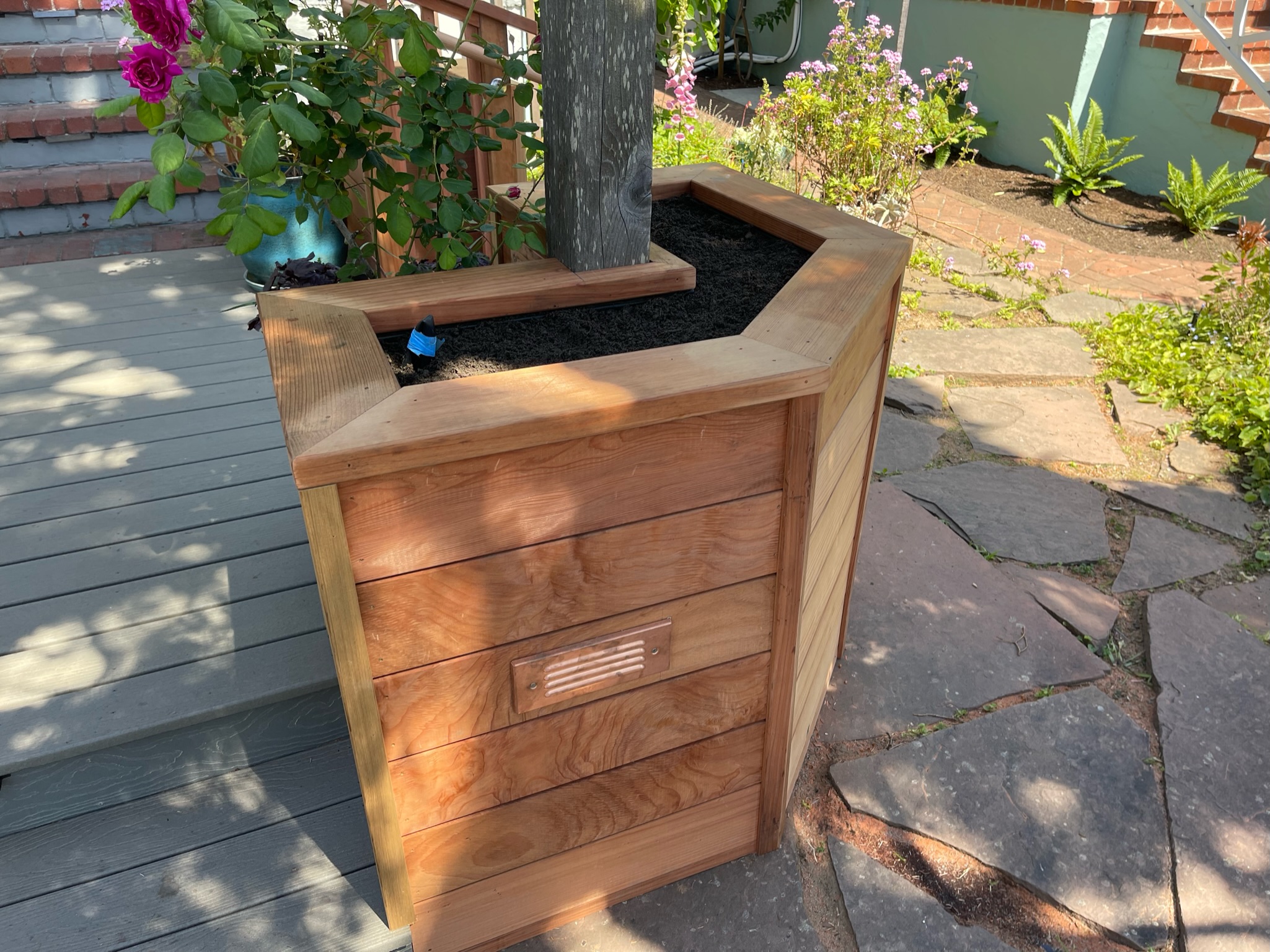 Planter box with tree placed by the deck, demonstrating effective use of outdoor space and potential for landscape enhancement.