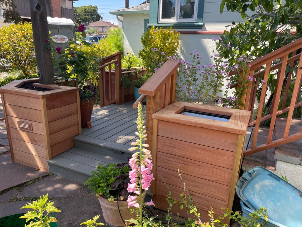 Small Berkeley front deck with steps, framed by wooden planters and railings; landscaping offers potential for curb appeal.