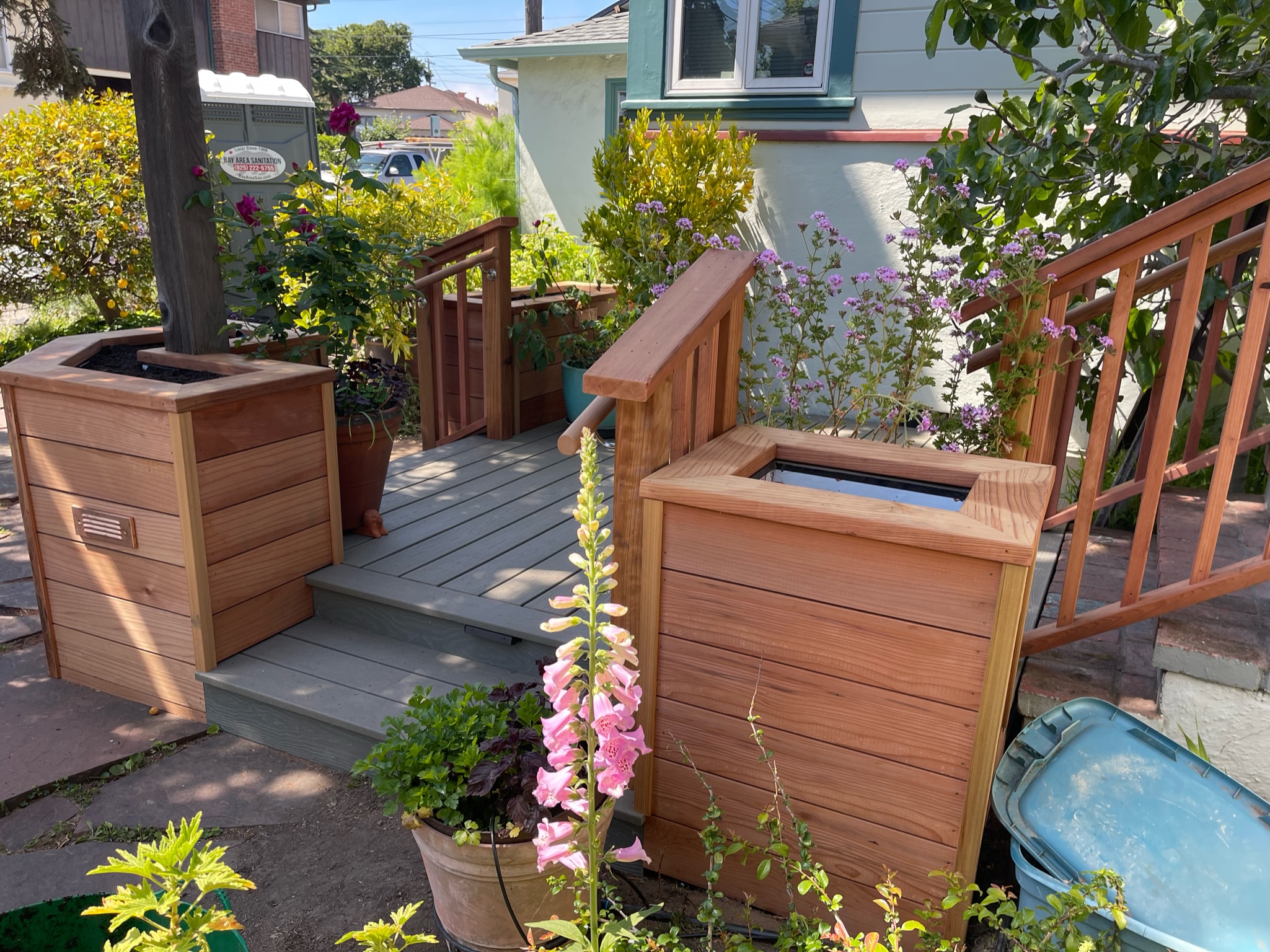 Small Berkeley front deck with steps, framed by wooden planters and railings; landscaping offers potential for curb appeal.