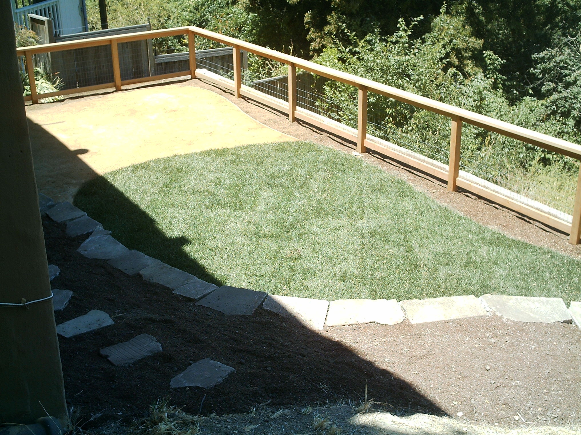 Crocker Highlands backyard with compact lawn, wooden fence, stone edging, and open soil/mulch areas suitable for landscaping.