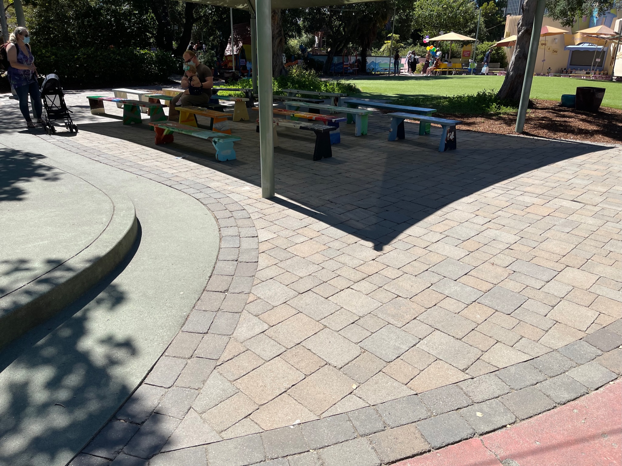 Paved outdoor area with canopy and mature trees for shade, offering potential for communal or recreational space redevelopment.