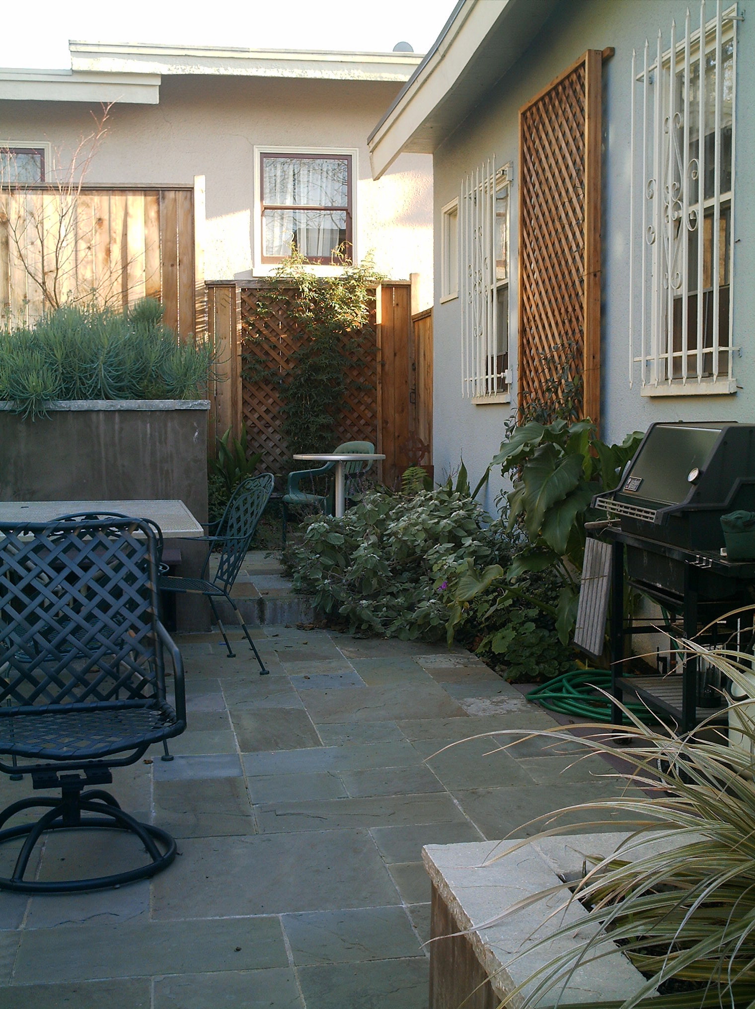 Compact backyard patio with established hardscaping, integrated planters, defined outdoor zones, and efficient use of space.