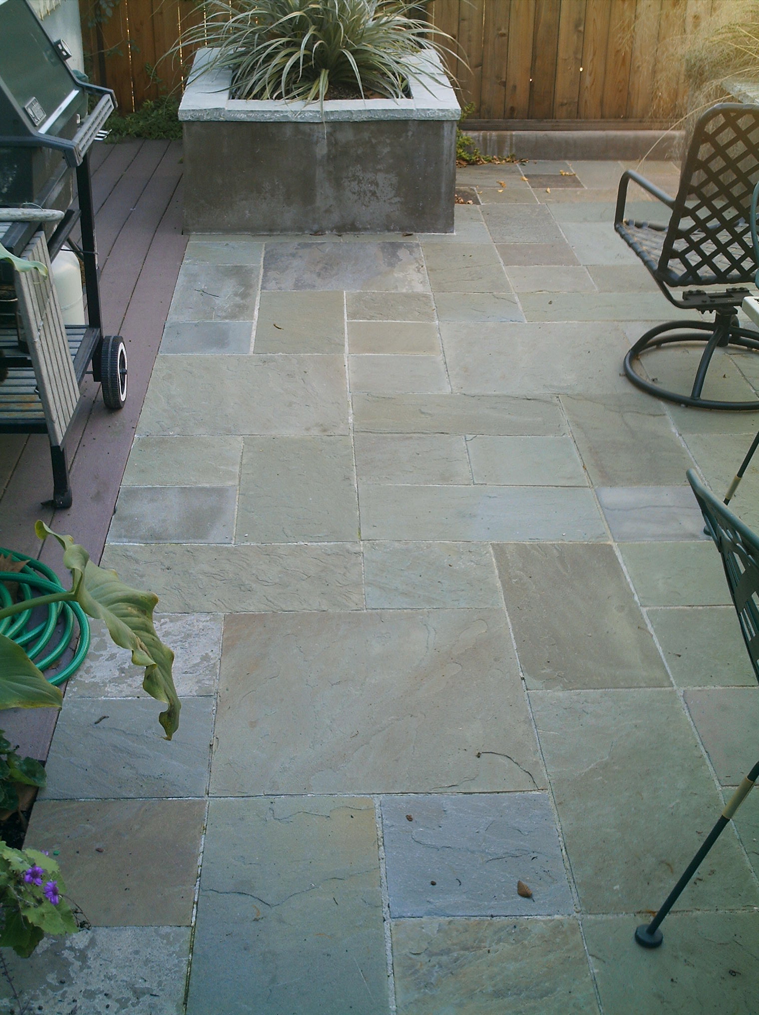 Rectangular backyard patio with durable stone tile flooring, well-defined edges, and fenced boundary—ideal for redevelopment potential.