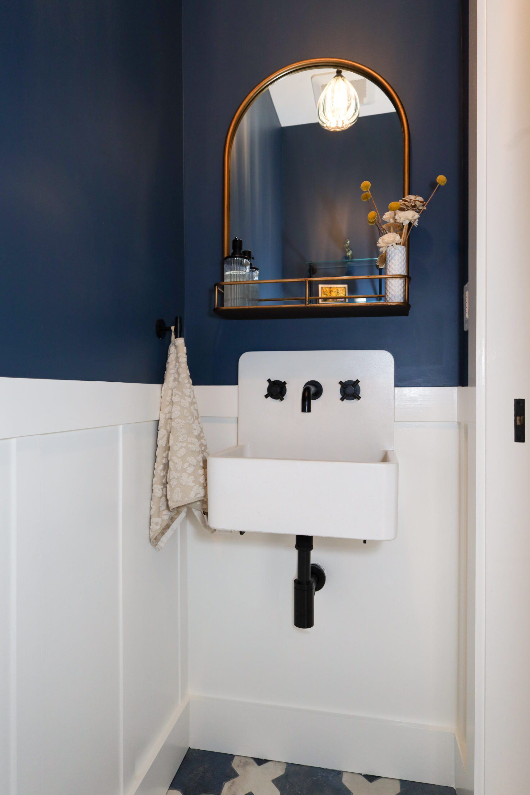 Compact bathroom with efficient wall-mounted sink, modern fixtures, and space-saving shelving optimizing storage and usability.