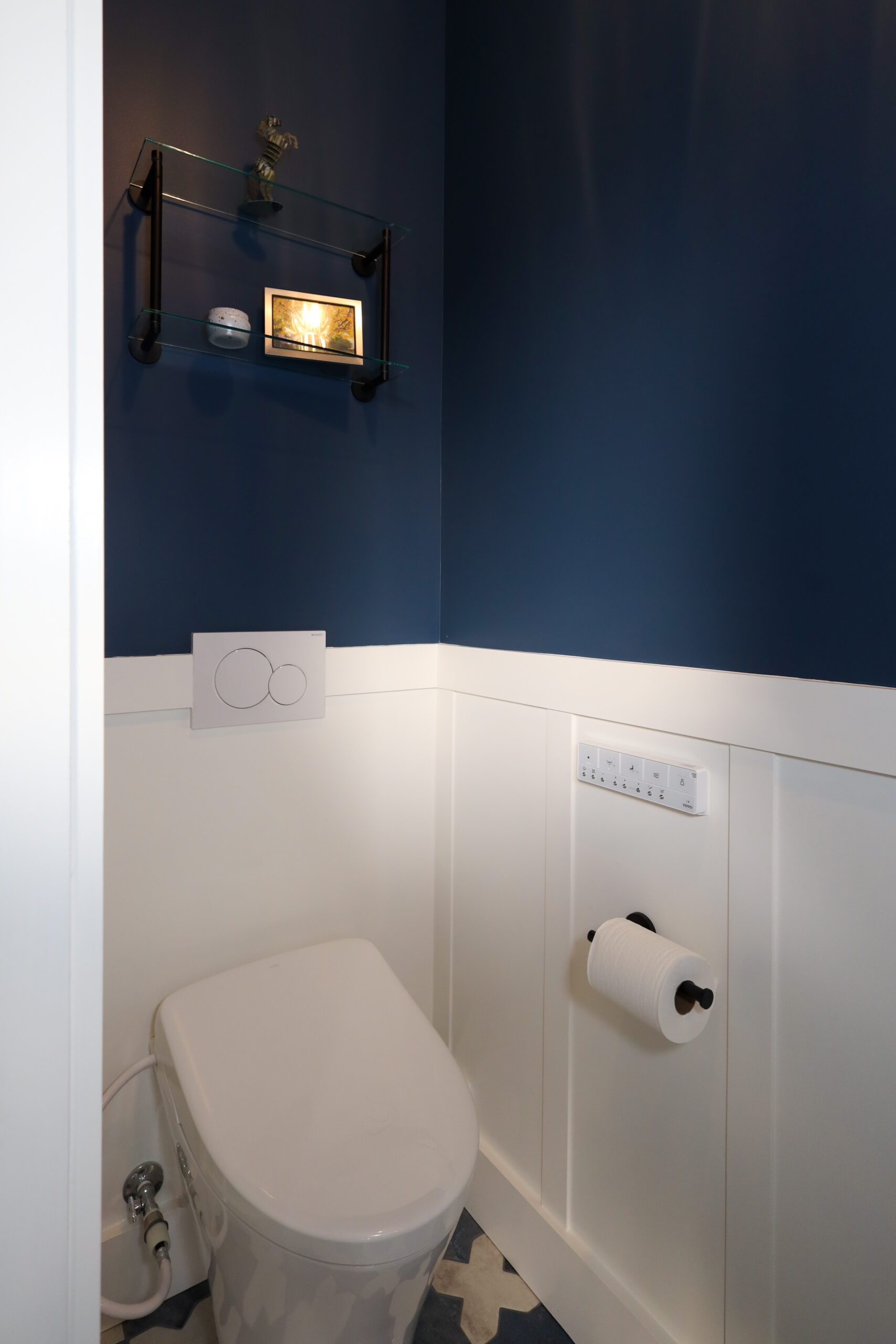 A compact bathroom features efficient use of space, with a modern toilet, accessible fixtures, and built-in shelving for storage.