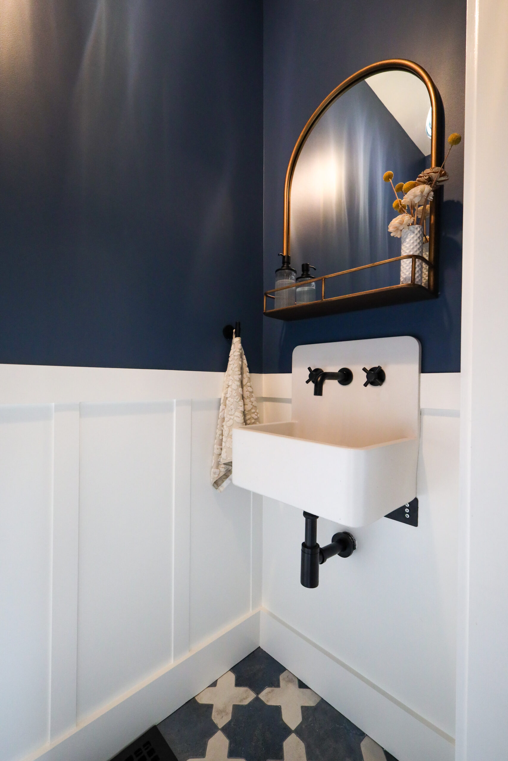 Compact bathroom corner featuring a space-saving wall-mounted sink, efficient fixture placement, and upgraded tile flooring.