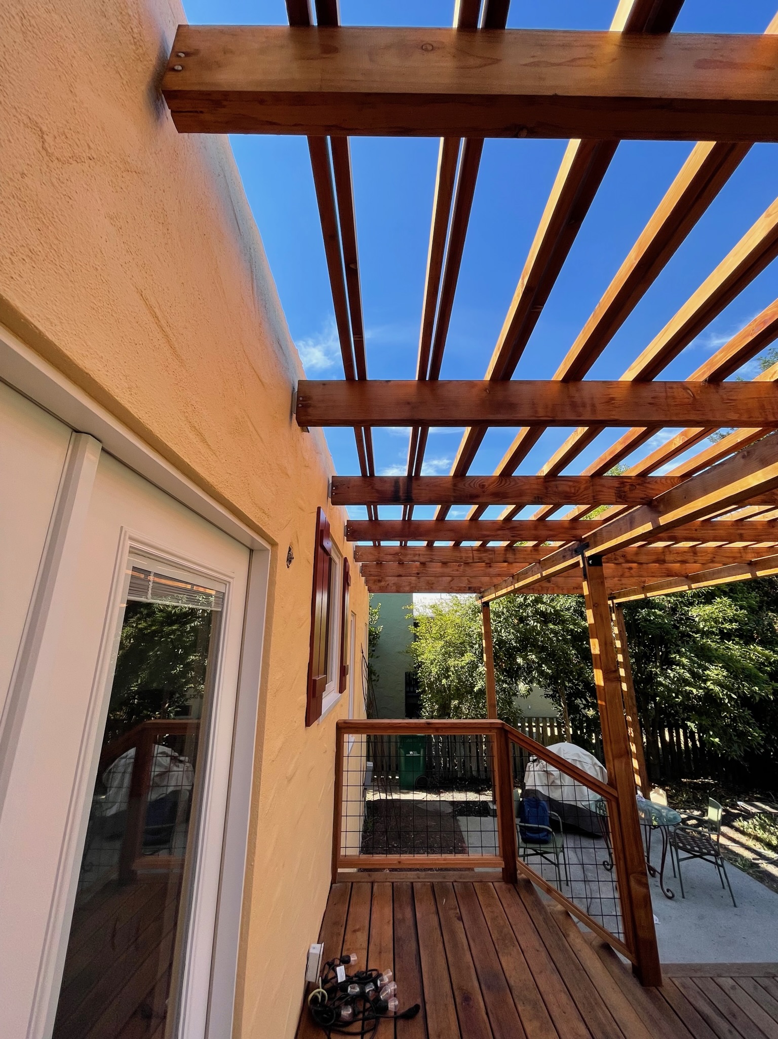 Wooden pergola structurally integrated with stucco house, extending over North Albany Deck, showing potential for outdoor upgrades.