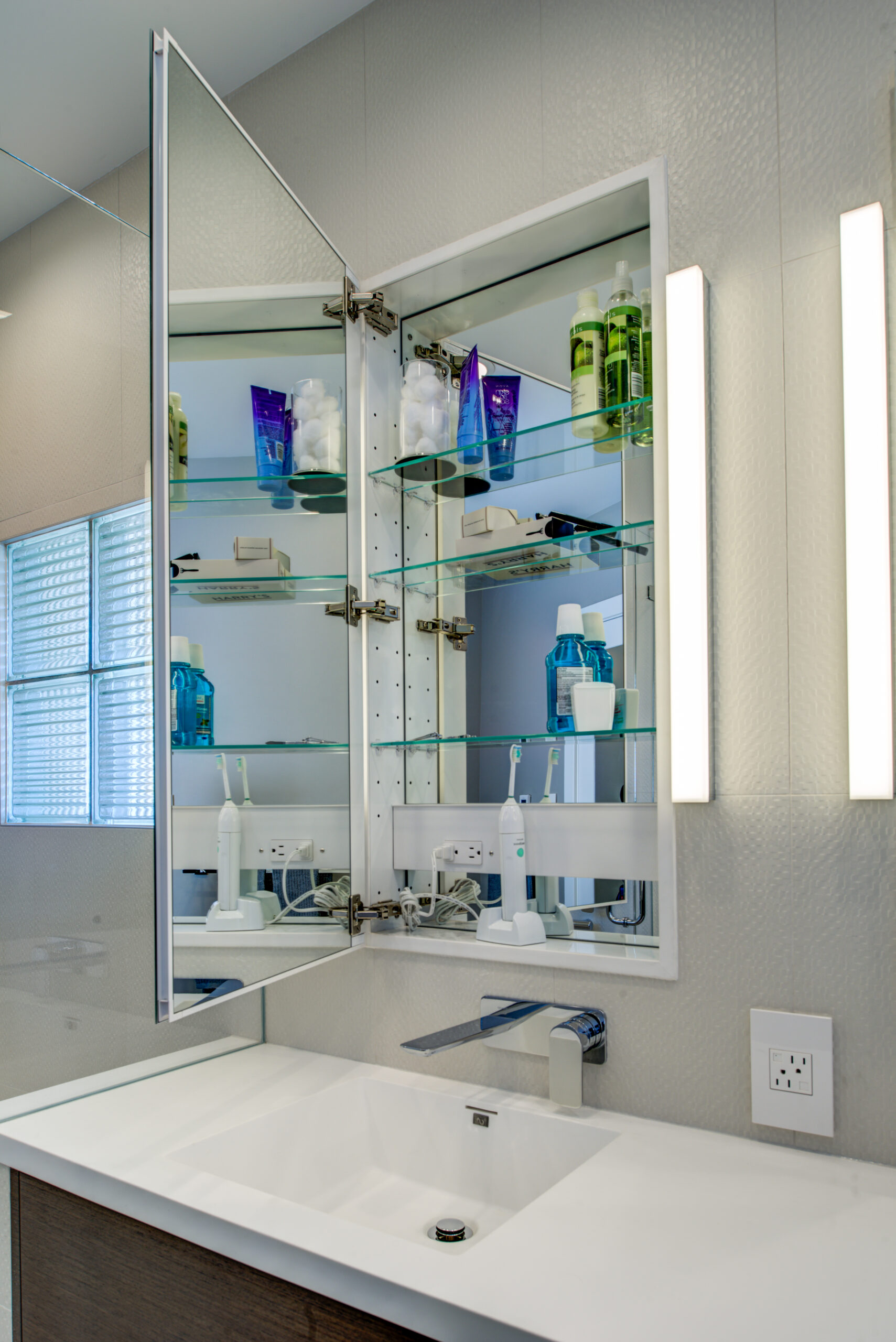 North Berkeley bathroom featuring built-in mirrored storage, practical vanity surface, plumbing fixtures, and organized shelving.