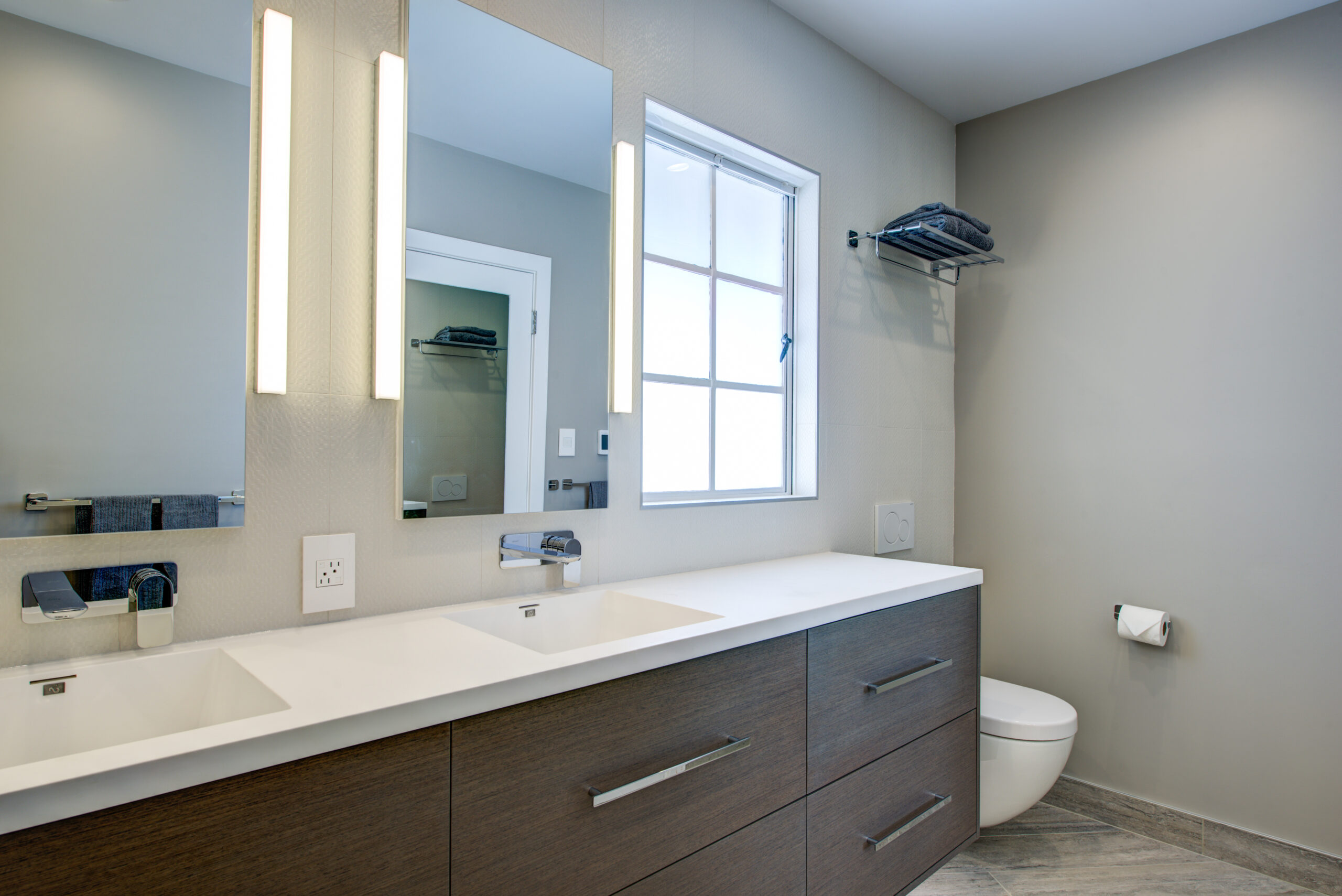 Modern North Berkeley bathroom with double sink, ample mirrored wall, upgraded lighting, ventilation window, and efficient layout.
