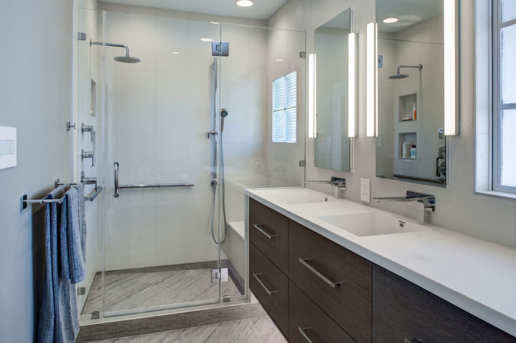 Modern North Berkeley bathroom with glass shower, dual-sink vanity, large mirror, ample lighting, and efficient layout.
