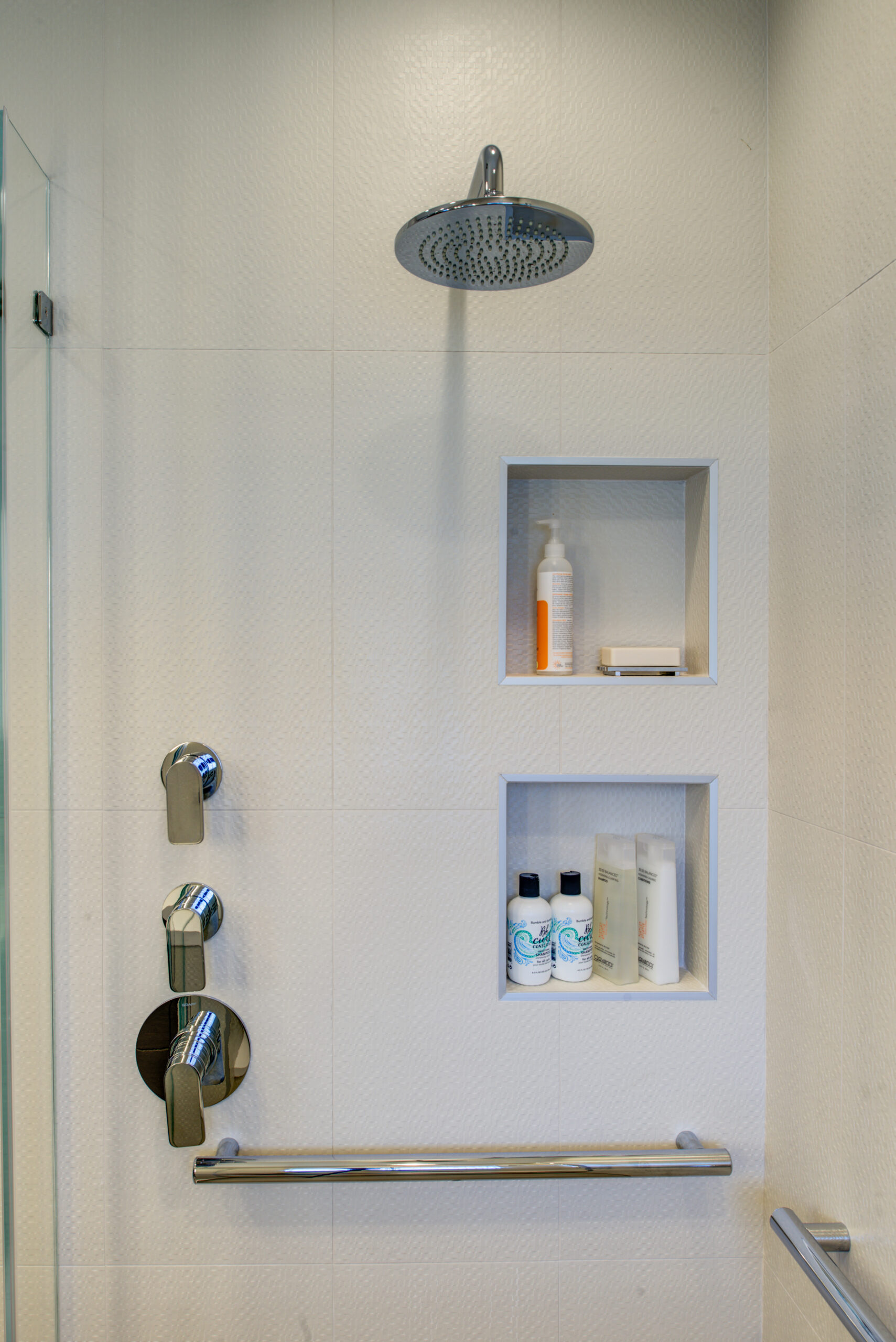 North Berkeley bathroom featuring updated fixtures, a rainfall shower system, accessibility grab bar, and built-in shelving for storage.