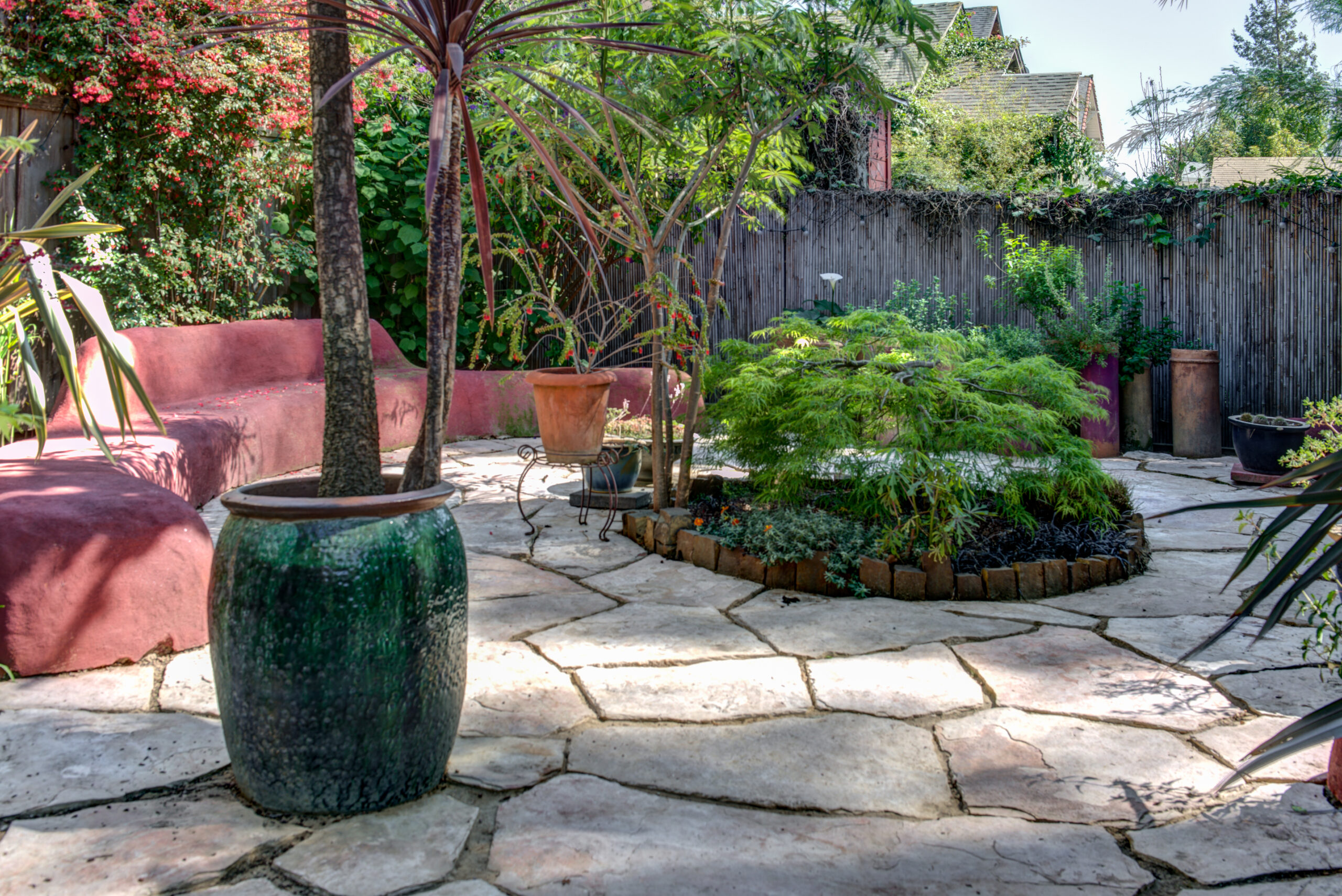 Backyard with durable stone paving, versatile planting areas, efficient raised bed layout, and perimeter privacy fencing.