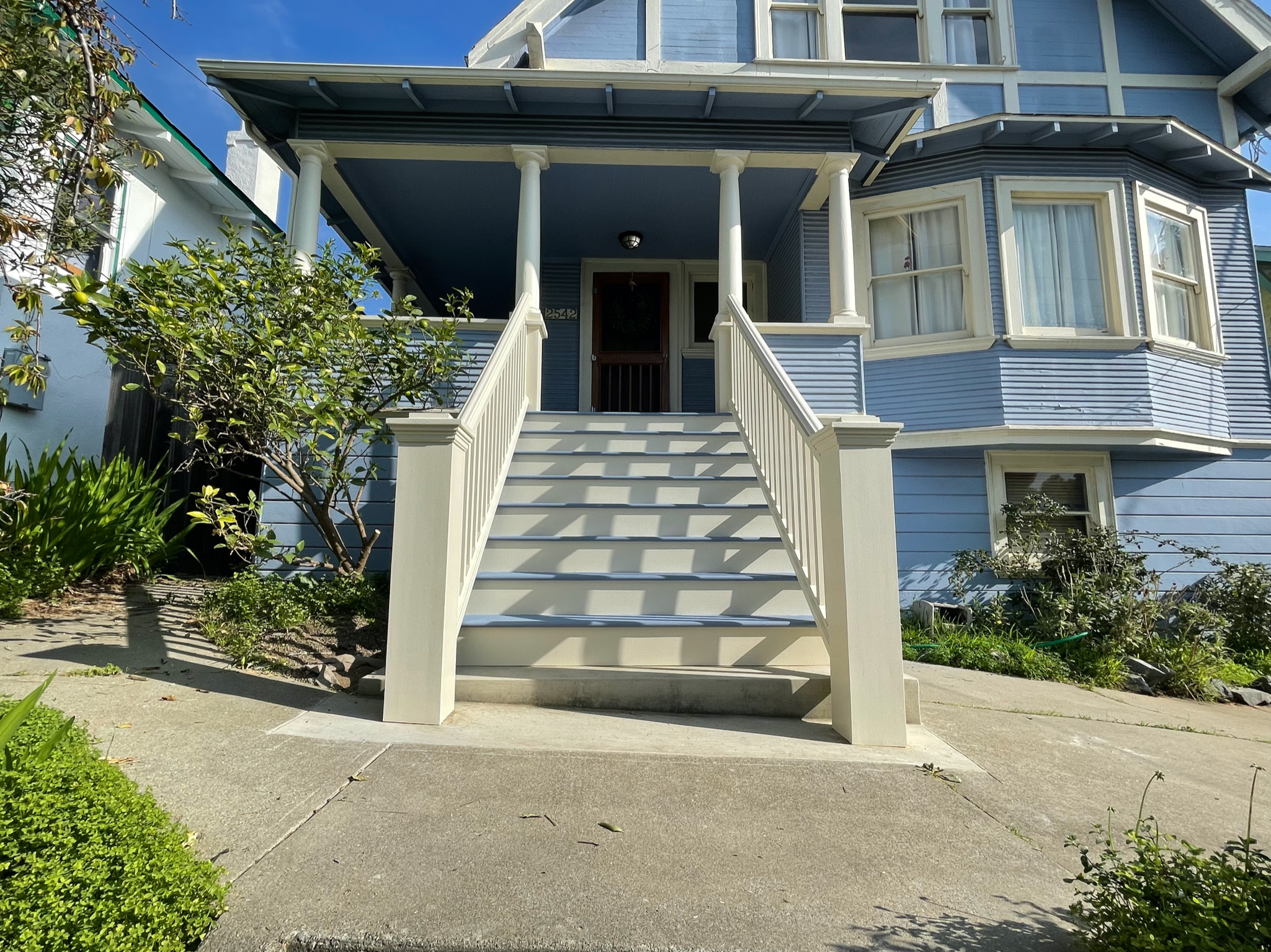 Oakland house with prominent front steps, spacious porch, bay windows, and sizable front yard offering redevelopment potential.