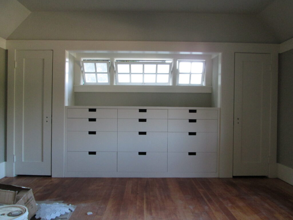 Built-in storage under three windows maximizes utility; wood floors offer solid potential. Lightweight packing material is present.