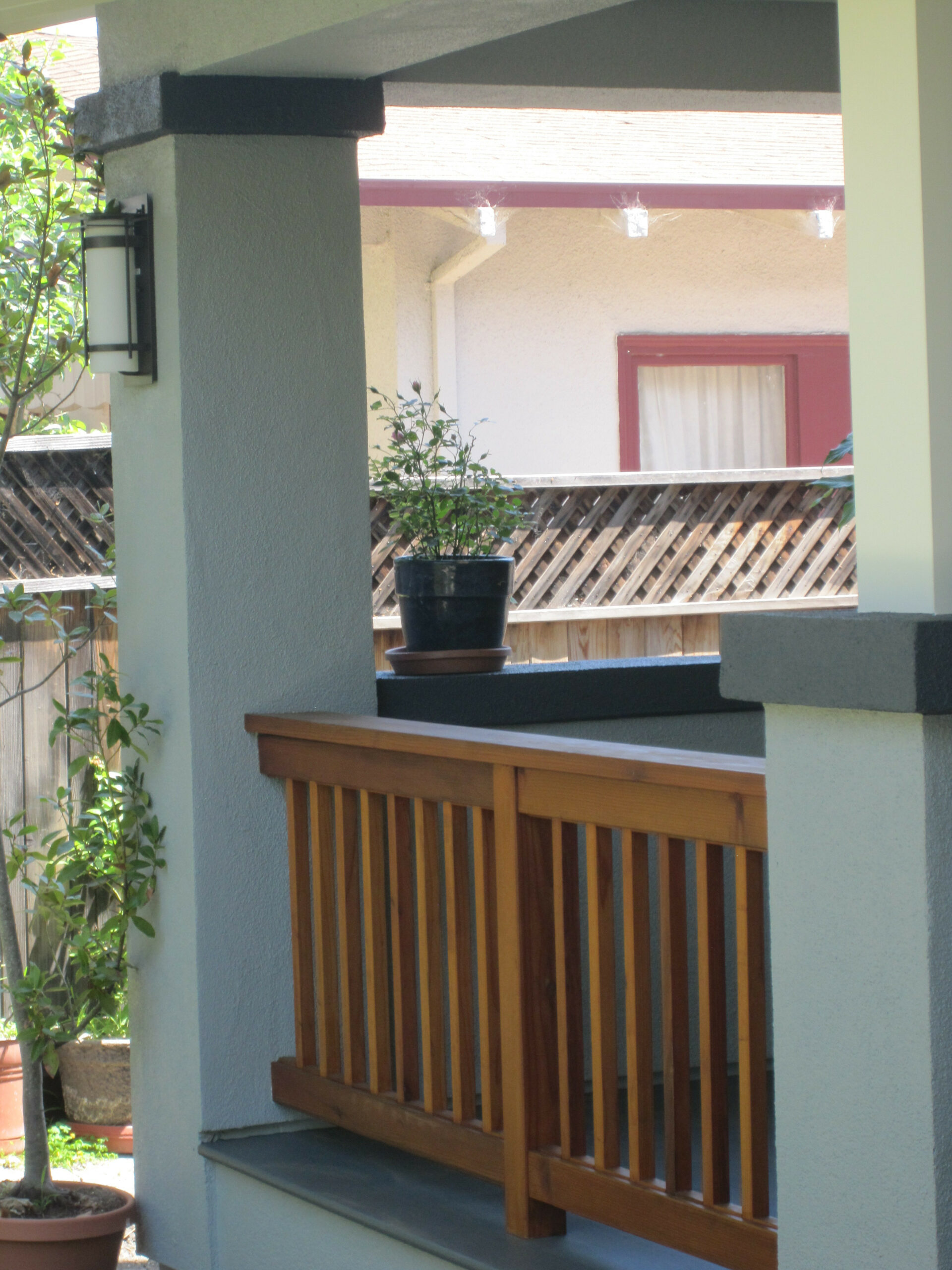 Deck features sturdy wooden railing; fenced yard provides privacy. Neighboring house proximity visible, indicating lot density.
