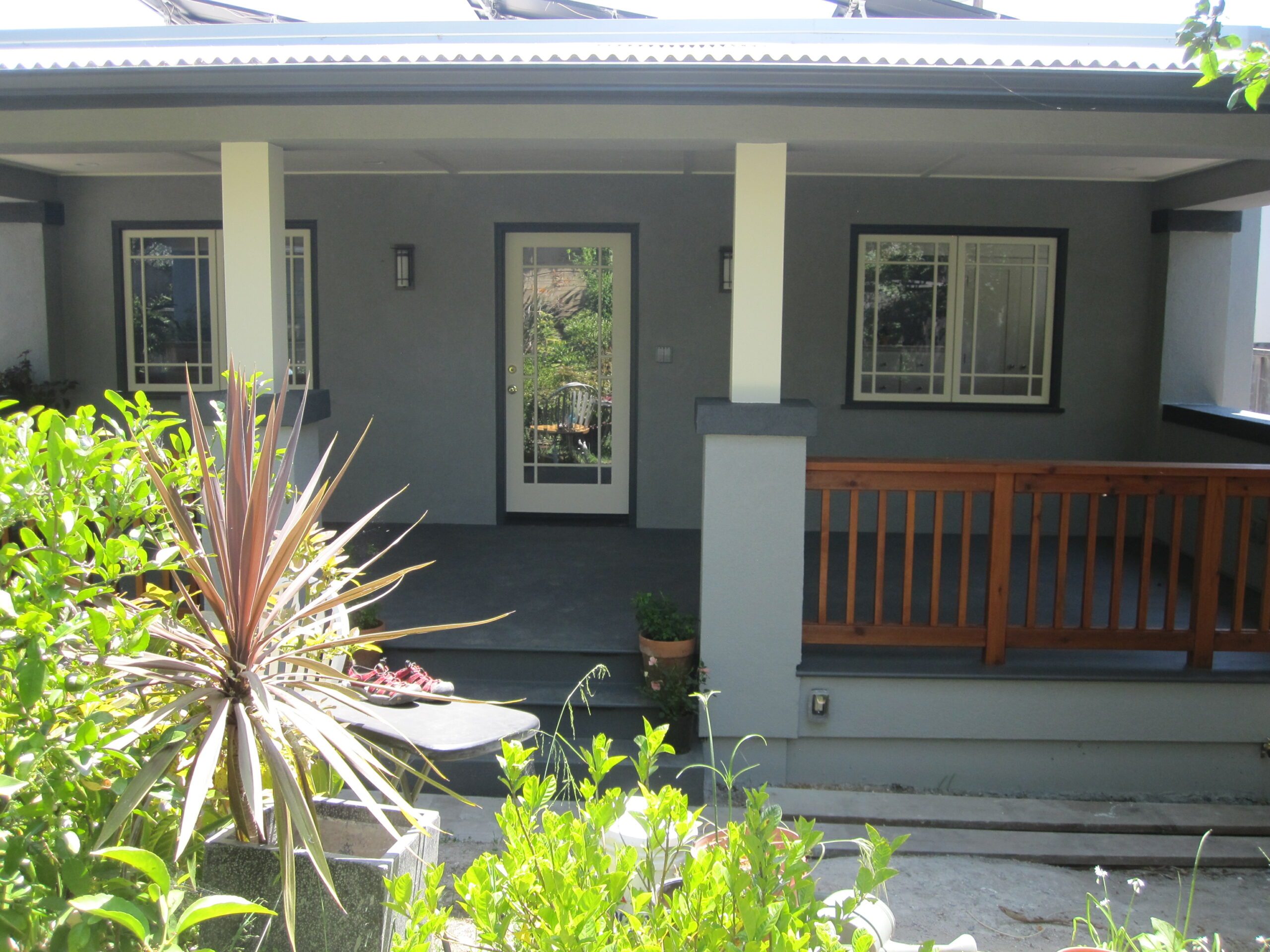 A structurally integrated front porch with glass door, dual windows, sturdy railing, and a seamless transition to a large deck.