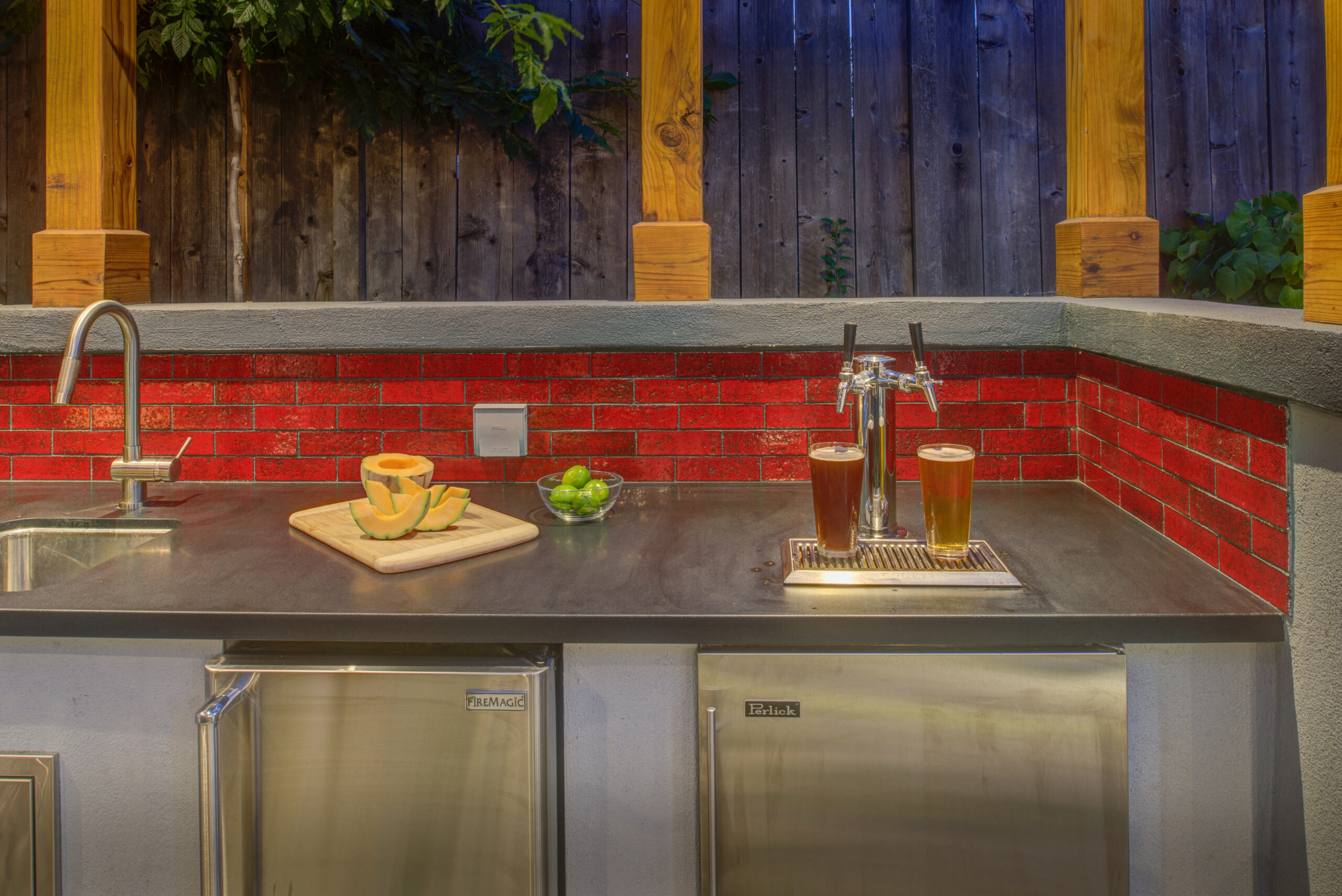 Oakland outdoor kitchen equipped with a sink, mini-refrigerators, prep area, and draft beer taps on a durable stainless counter.