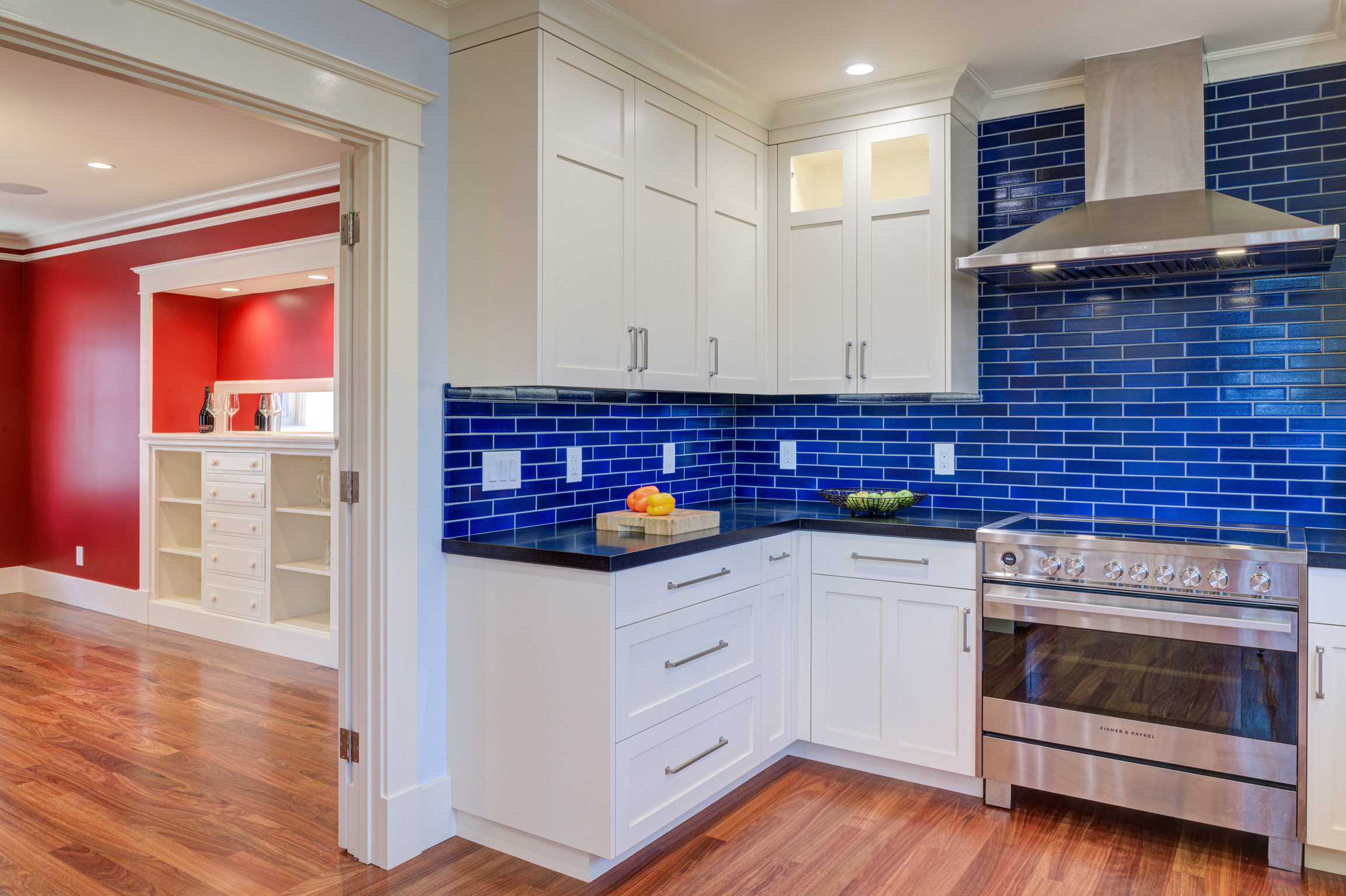 Oakland kitchen featuring updated cabinetry, quality tile backsplash, modern appliances, hardwood flooring, and open floor plan.