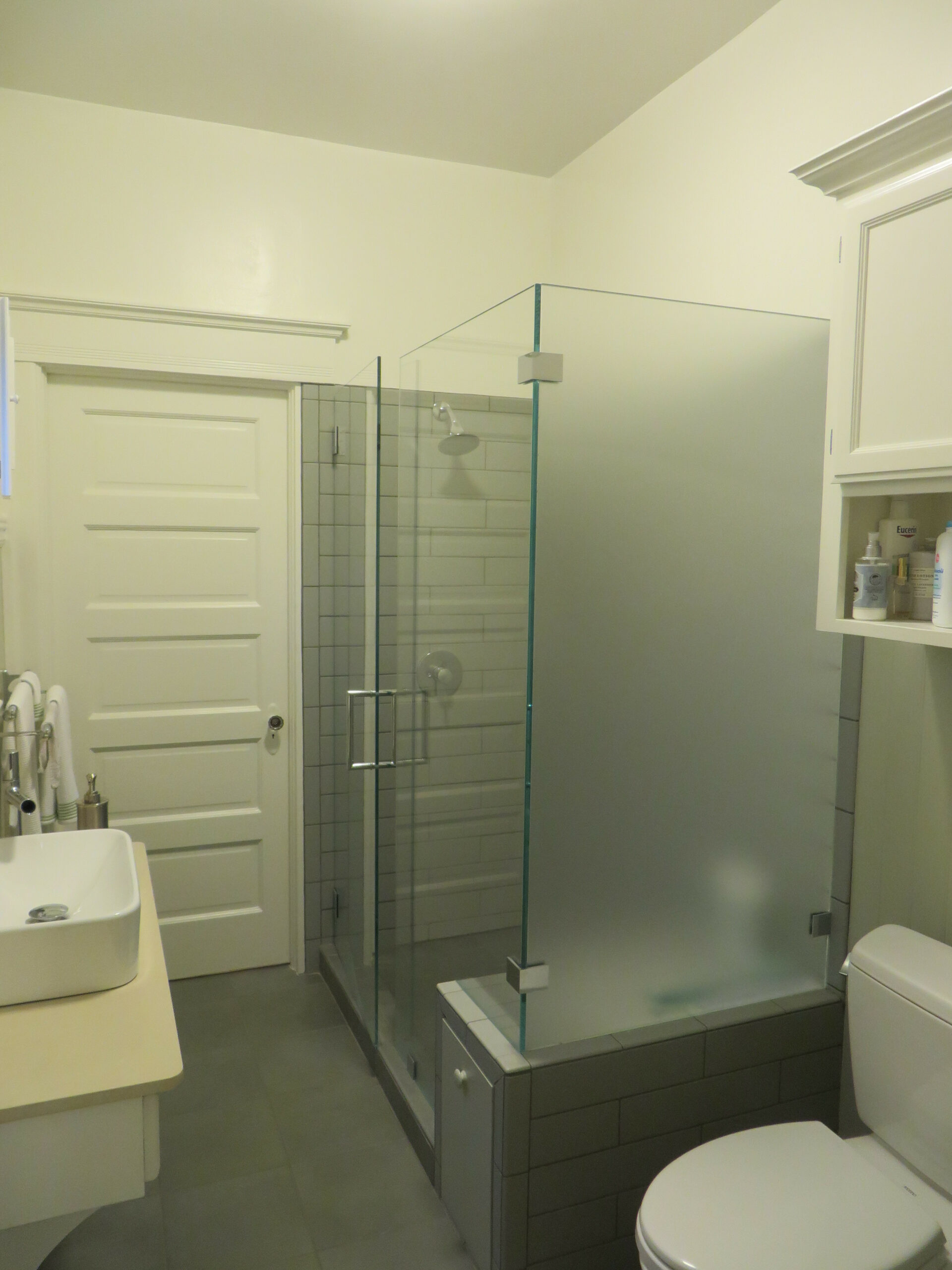 Modern Piedmont bathroom with updated fixtures, glass shower enclosure, frosted panels, and efficient storage maximizing space.