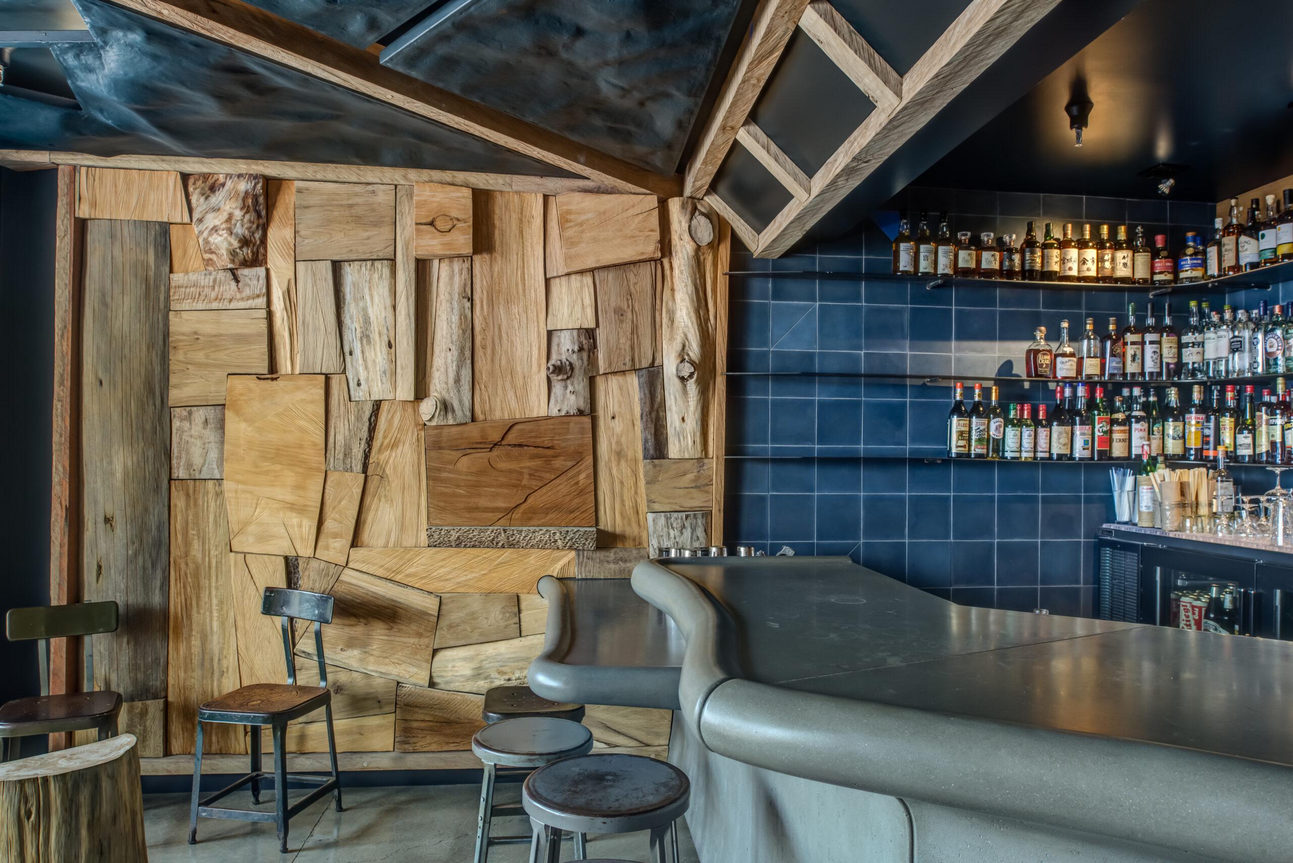 Modern bar in Rockridge Oakland with geometric accent wall, tiled backsplash, built-in shelving, and durable concrete counter.