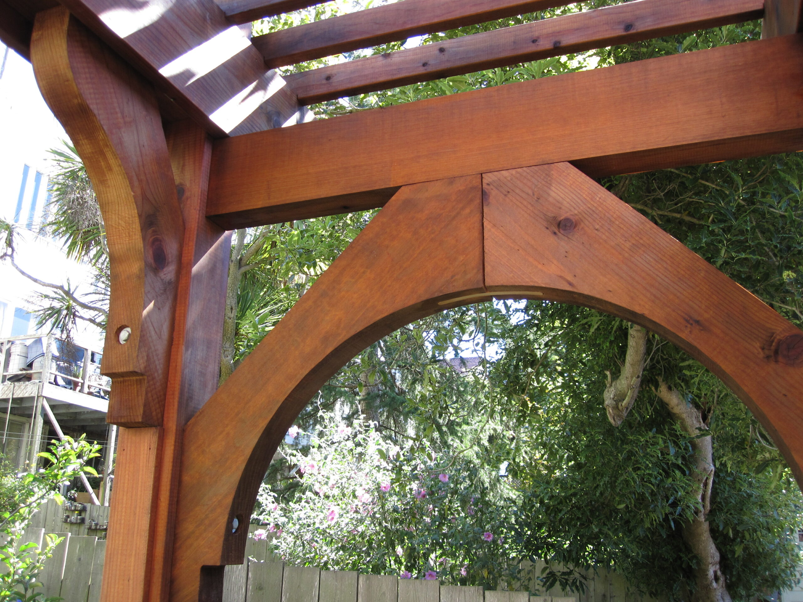 Close-up of sturdy pergola beams and bolted joints, highlighting structural integrity and potential for renovation in a backyard setting.