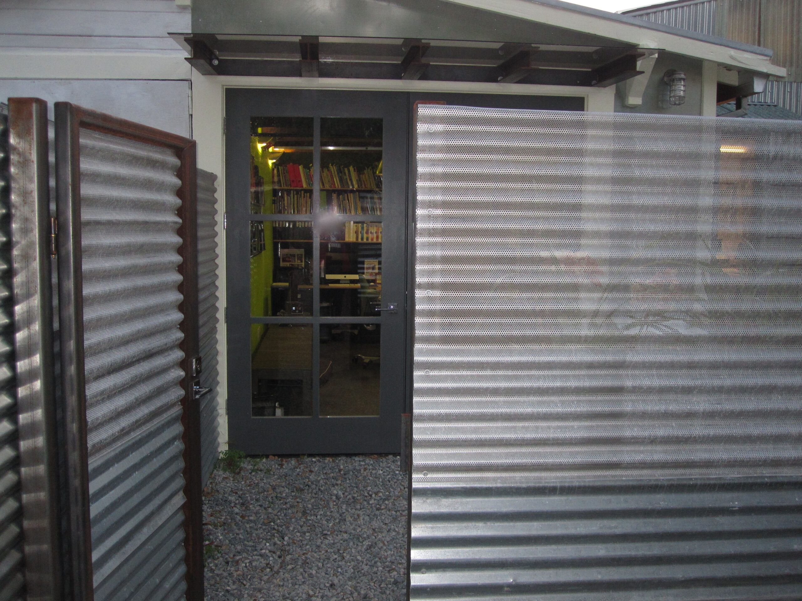 Partially open metal gate and glass entry suggest secure access; interior space appears open with potential for flexible layout.