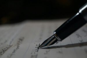 A close-up of a fountain pen writing on lined paper, emphasizing careful planning and detailed documentation.