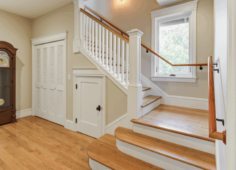 Staircase with railings, window, and under-stair storage adds functionality and potential to optimize space in a residential renovation.