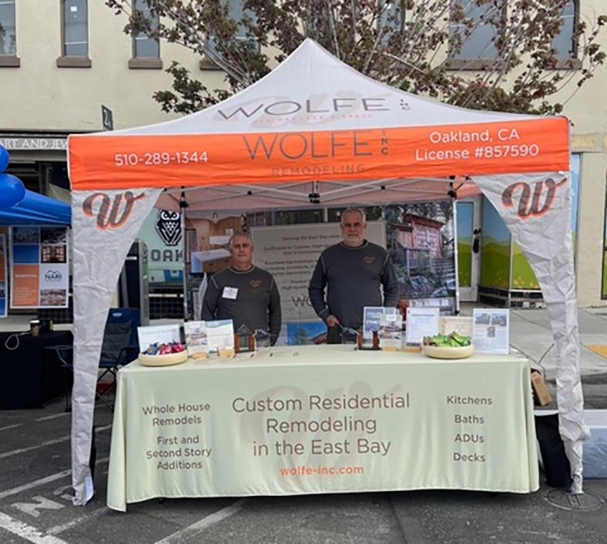 Two men at a Wolfe Remodeling booth share details on local residential renovation, project management, and redevelopment expertise.