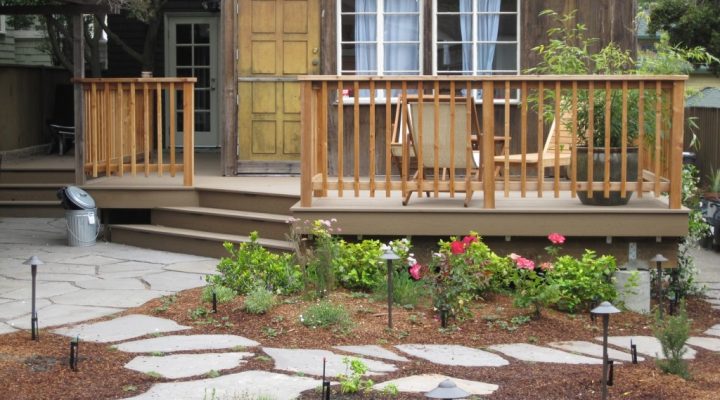 Spacious deck with sturdy railings, direct garden access via stone path, low-maintenance landscaping and durable hardscape elements.