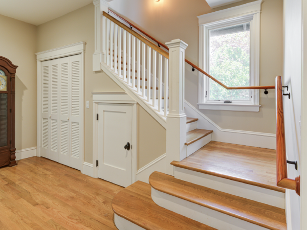 Staircase with railings, window, and under-stair storage adds functionality and potential to optimize space in a residential renovation.