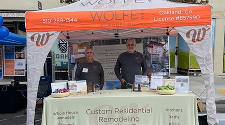 Two men at a Wolfe Remodeling booth share details on local residential renovation, project management, and redevelopment expertise.